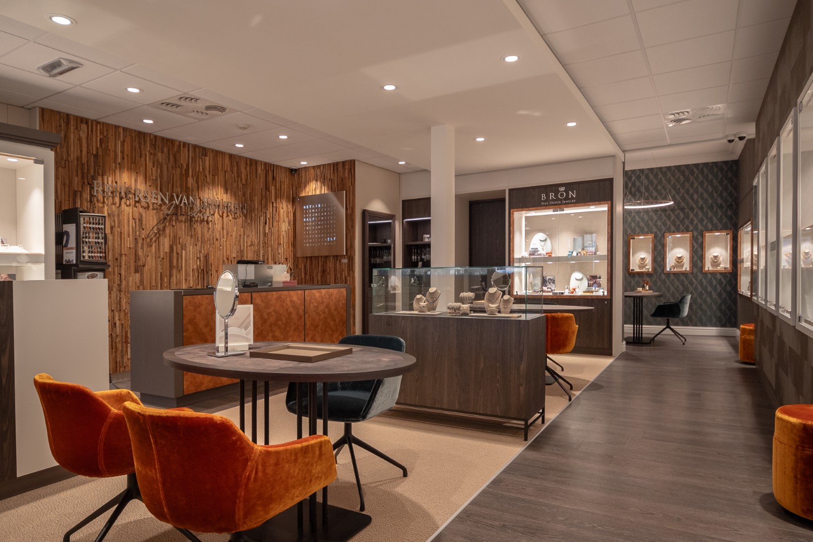 Restyling of complete store interior of jeweler Reijersen van Buuren with wooden floors and wooden walls and back wall and showcases built into the wall with lighting.