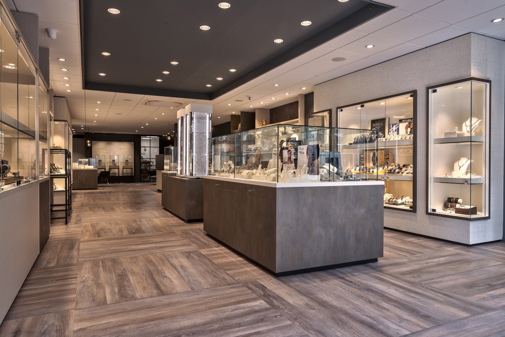 Shop design for a jewelry store in Harderwijk with wooden floor and many display cases.