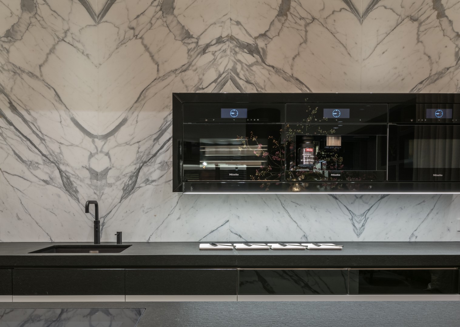 Achterwand van natuursteen en Miele apperatuur in maatwerk keuken met klasieke zwart-wit patroon in modern jasje.