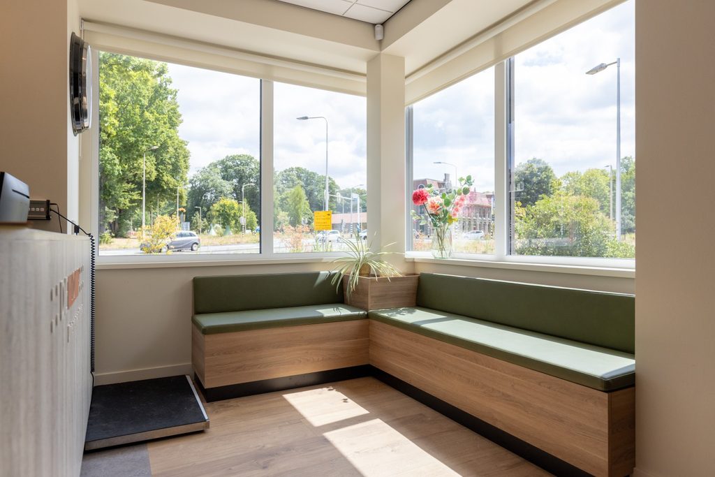Warmer Eingangsbereich der Tierarztpraxis De Klomp in Ede mit abgerundetem Empfangstresen